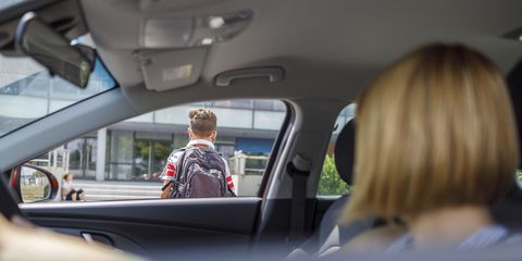 woman in a car observing her son entering school
