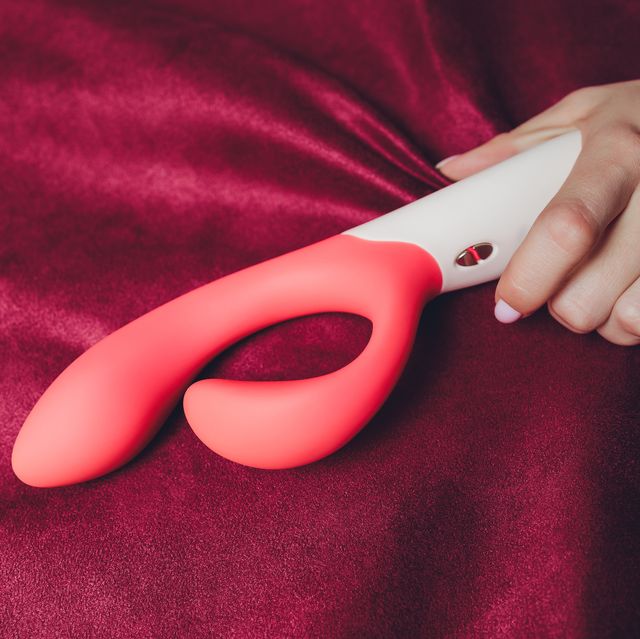 woman in bedroom holding vibrator in hand