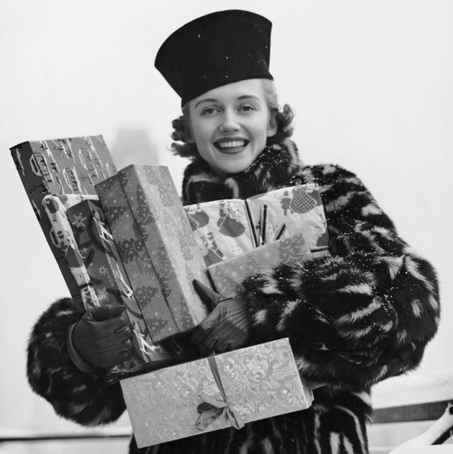 woman in fur coat holding christmas gifts