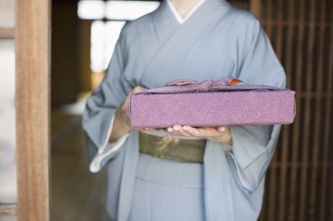 Woman in kimono holding gift, mid section