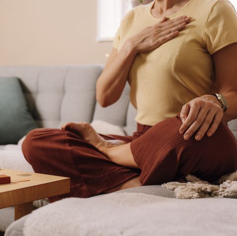 woman indoors relaxing meditating and doing breathing exercises