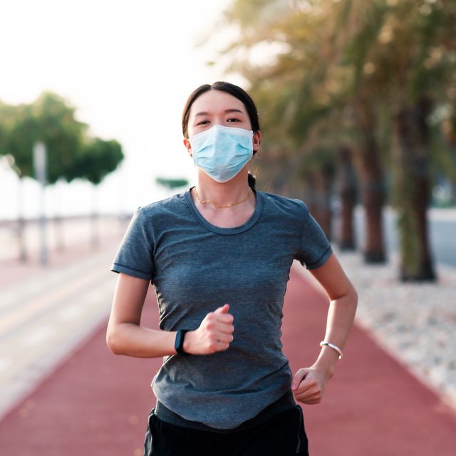 woman jogging on the running track wearing protective mask