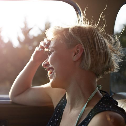 Woman laughing in car with open window