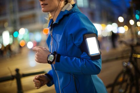 Woman listening music while jogging in city