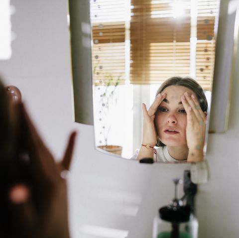 Woman looking in bathroom mirror