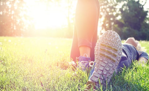 Woman lying down on grass and relaxing after workout.