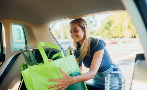 woman packing shopping bags full of groceries into the car trunk