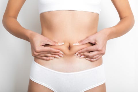 Woman pinching her stomach on white background