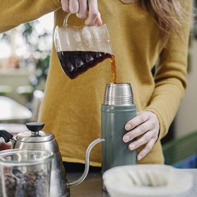 a woman pouring coffee into a flask
