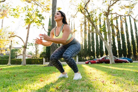 Woman practicing jump squats in park Женщина, практикующая прыжковые приседания в парке