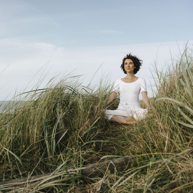 woman practicing yoga in beach dune