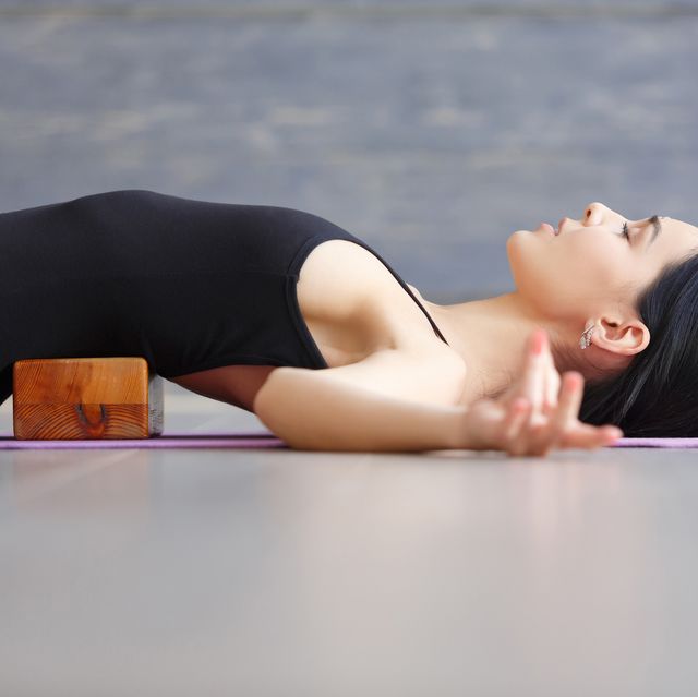woman practicing yoga indoors with a yoga block