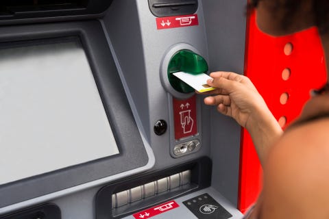 Woman pushing credit card at cash dispenser, partial view Woman pushing credit card at cash dispenser, partial view