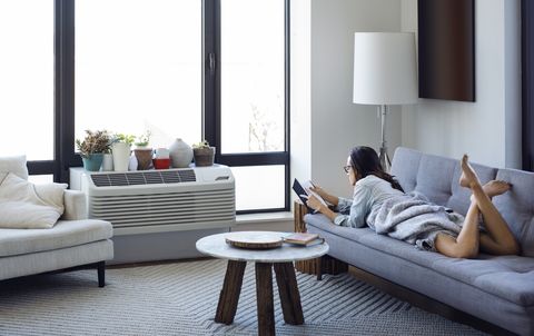 woman reading book while lying on sofa at home