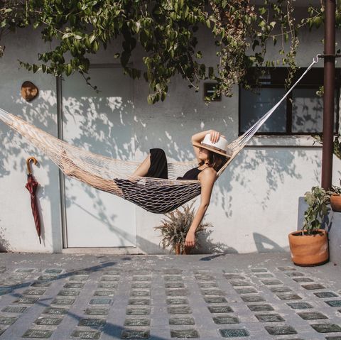 woman relaxing in hammock against wall at yard