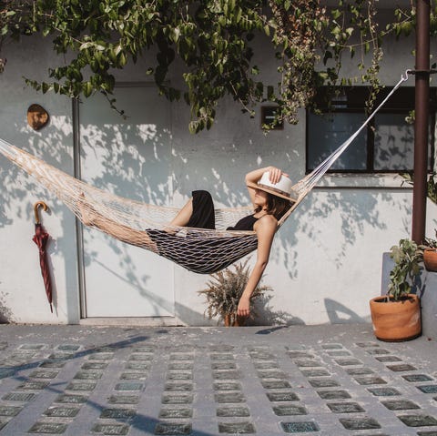 woman relaxing in hammock against wall at yard