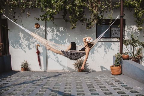 Woman Relaxing In Hammock Against Wall At Yard
