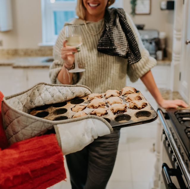 a woman removes freshly baked home made mince pies from an oven