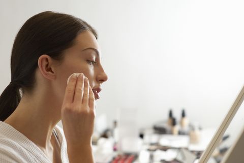 woman removing makeup with products in background