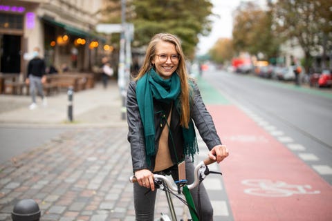 Una mujer pasea en bicicleta por una ciudad una mujer con gafas y una sonrisa montada sobre dos ruedas