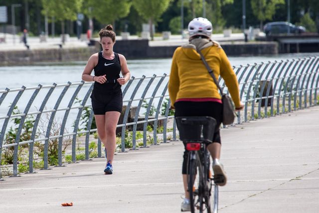una mujer corre junto a un río y se cruza con otra que va en bici durante el confinamiento por el covid 19 en francia