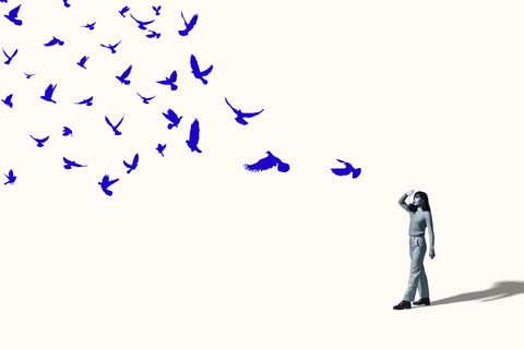 woman shielding eyes in front of flying blue birds