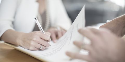 woman signing contract at desk at car dealership