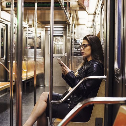 A woman sitting in a metro subway carriage looking at her cellphone.
