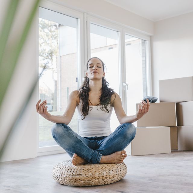 woman sitting on cushion in her new apartment, meditating