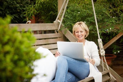 Woman sitting on swing using laptop