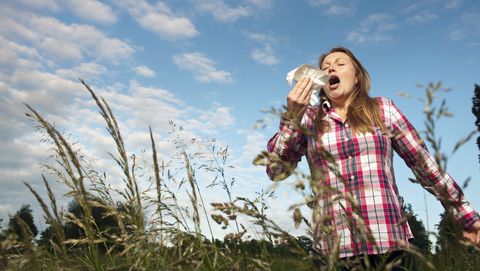 vrouw niest in hoge gras met witte zakdoek