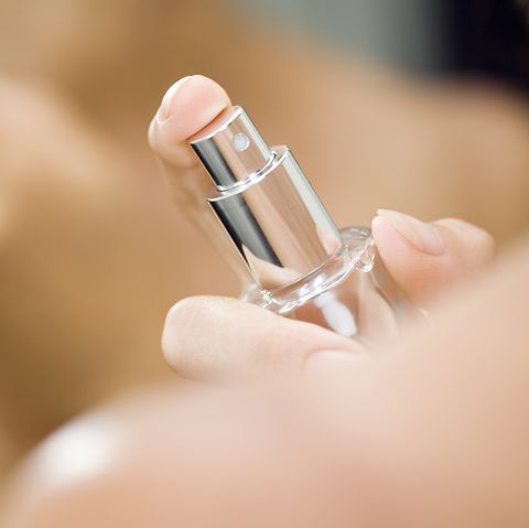 Woman spraying perfume on neck, close up