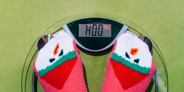 woman standing on the scales in christmas fun red green socks with snowman background the problem of excess weight gained during the holiday new year