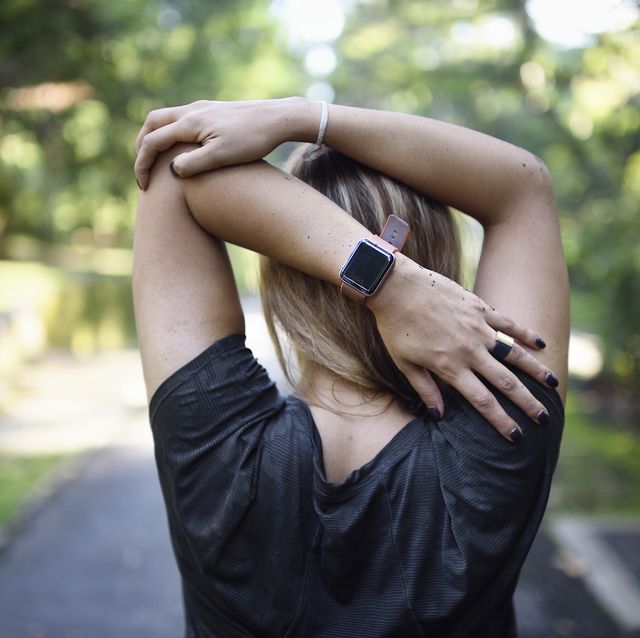 Woman stretching on a trail with a fitness tracker