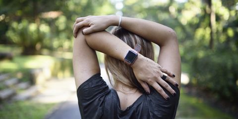 woman stretching on a trail with a fitness tracker
