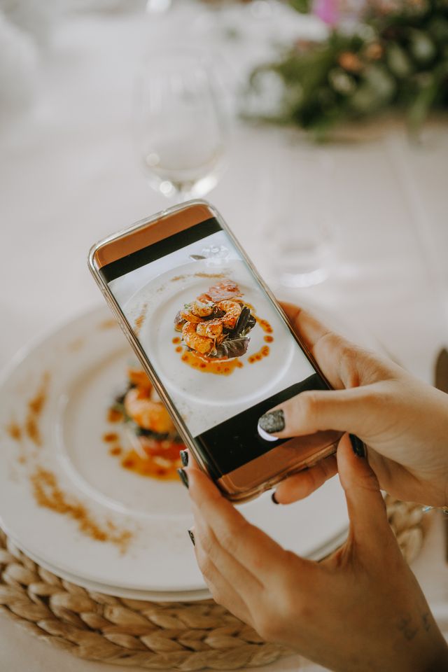 Woman taking photo of plate of food with smartphone