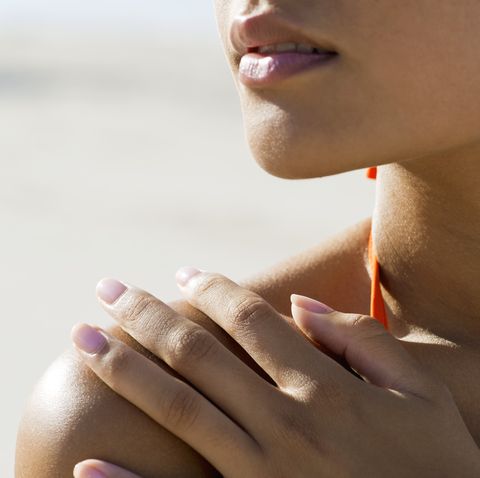 woman touching bare shoulder at the beach, cropped