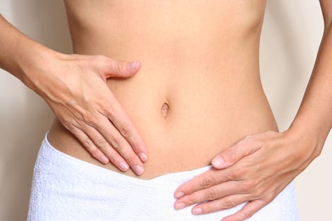 a woman touching her stomach wearing a white towel