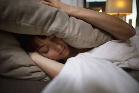 woman unable to sleep covering ears with pillow