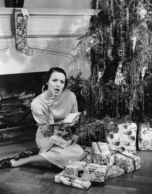 mujer debajo de un árbol de navidad haciendo una lista