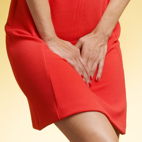 woman in red dress pressing hands on lower abdomen