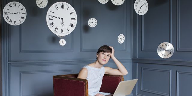 woman using laptop with hanging clocks above