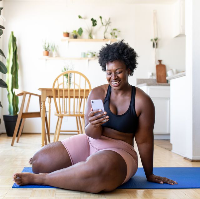 woman using phone after exercising at home