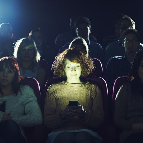 woman using phone during movie at cinema