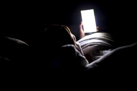 woman using smartphone for looking up social medial at late night lying in bed, internet addicted