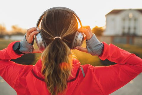 woman wearing headphones and listening music on morning run view from behind