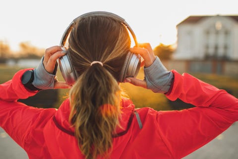 Woman wearing headphones and listening music on morning run. View from behind woman wearing headphones and listening music on morning run view from behind