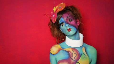 woman with colorful body paint posing on pink background