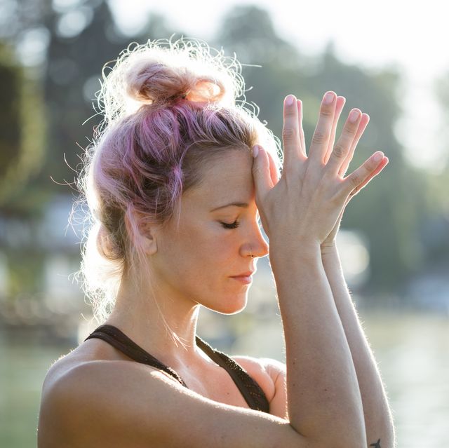 woman with dyed hair meditating at a lake