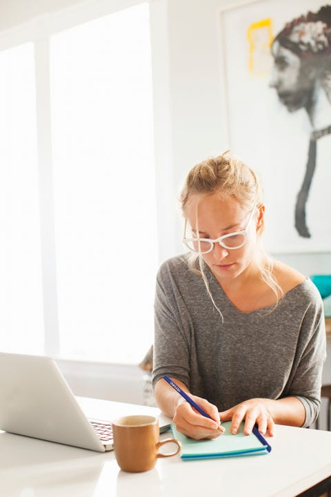woman writing in journal at coffee table woman writing in journal at coffee table